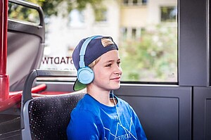 Symbolbild Junge sitzt im Bus und hat Kopfhörer auf